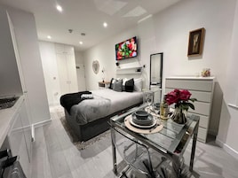 Un dormitorio moderno con cama, mesita de noche, cómoda y televisor montado en la pared.