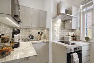 Una cocina moderna con armarios blancos, encimera de mármol y horno empotrado.