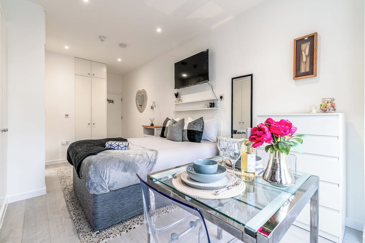 Une chambre à coucher moderne avec un lit, une table de chevet et un téléviseur fixé au mur.