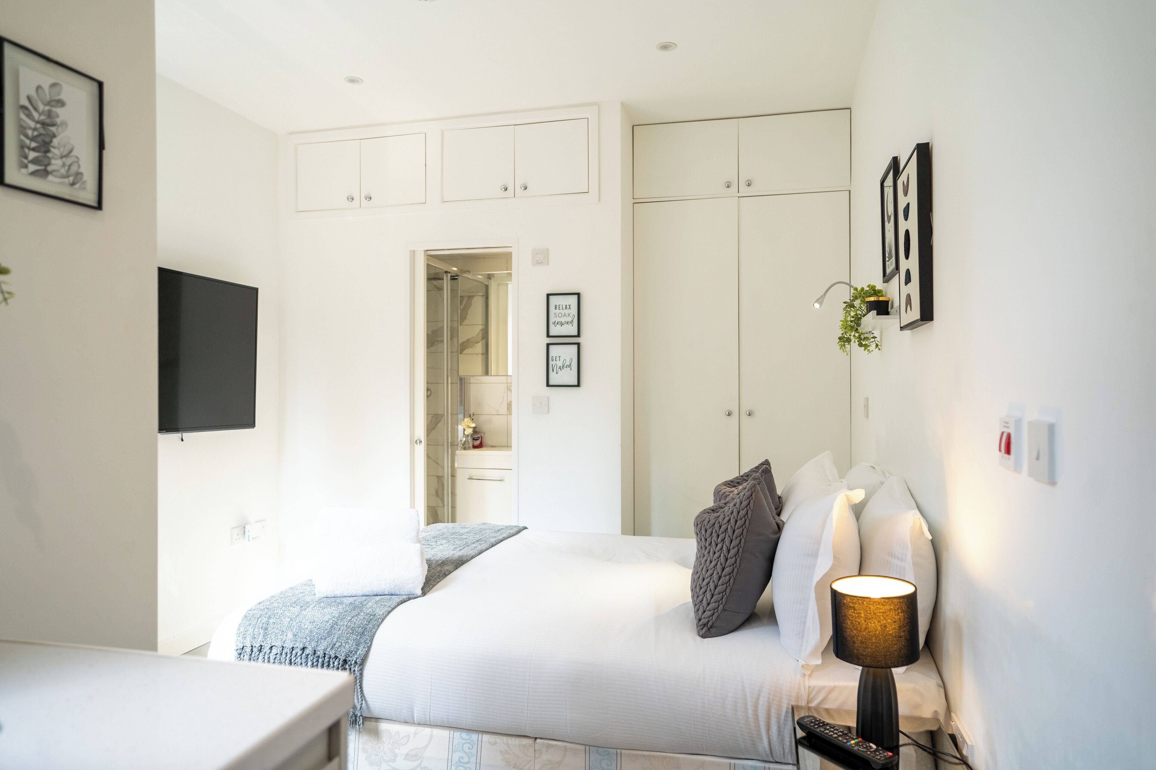 A modern bedroom with a bed, bedside table, and a TV mounted on the wall.