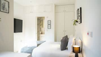 A modern bedroom with a bed, bedside table, and a TV mounted on the wall.