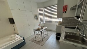 Una cocina compacta con lavamanos, estufa y ventana con persianas.