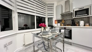 Una cocina moderna con una mesa de comedor de vidrio, electrodomésticos de acero inoxidable y vistas a través del ventanal.
