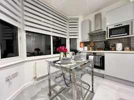 Una cocina moderna con una mesa de comedor de vidrio, electrodomésticos de acero inoxidable y vistas a través del ventanal.