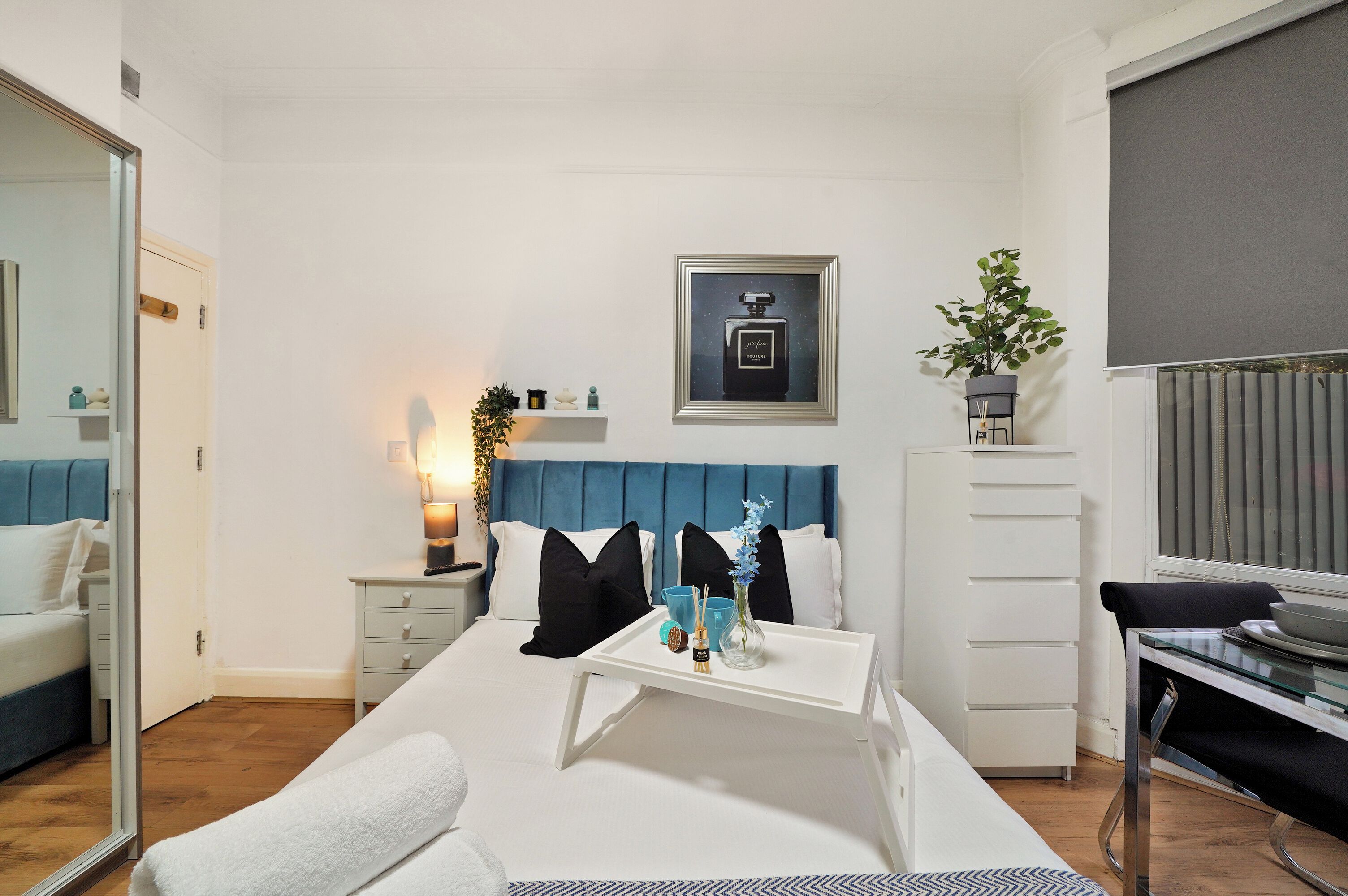 Una habitación de hotel moderna con una cama, una mesita de noche y un pequeño escritorio con una silla.