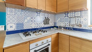 Una cocina con armarios de madera, una estufa a gas y baldosas con un estampado azul y blanco.