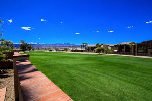 A well-maintained lawn, a brick pathway, and a building with a flat roof and large windows. - Luxury 5-Star Couples Retreat with Home Theater, Golf Course and Views. (Lake Havasu City)