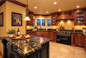 A kitchen with dark wood cabinets, a marble countertop, a built-in oven, and a window with a view.