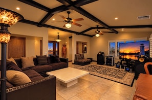 A living room with a sofa, coffee table, and a television displaying a sunset view.
