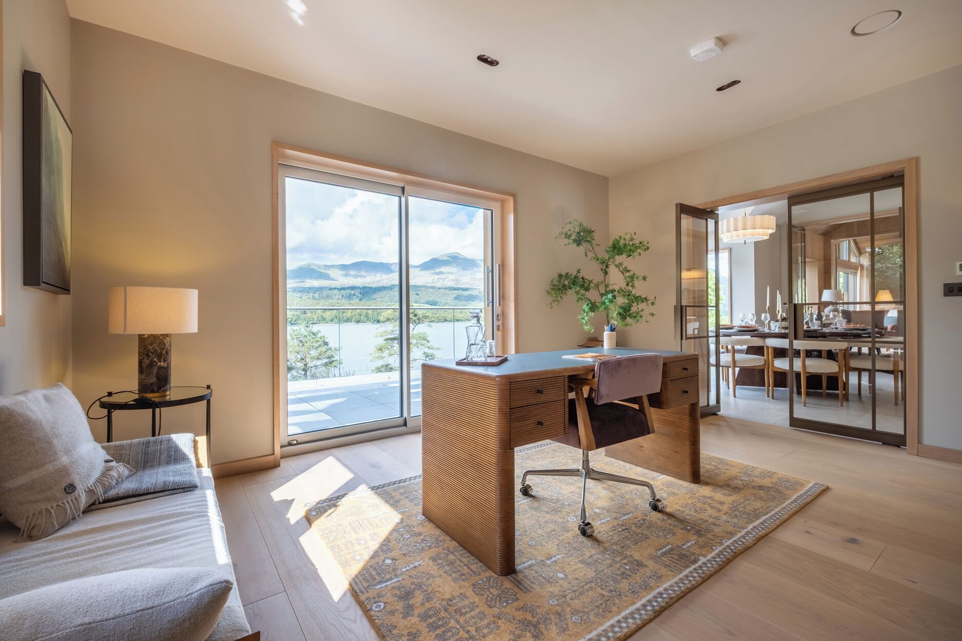 A modern room with a large window, a desk, and a dining area.