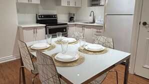 Cozinha moderna com armários brancos, fogão de aço inoxidável e geladeira branca.