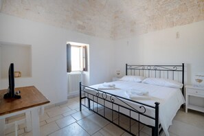A bedroom with a bed, a desk, a window, and a radiator.