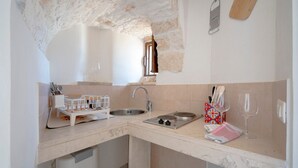 Una cocina con un arco de piedra, un fregadero, una estufa y una encimera con tabla de cortar y bloque para cuchillos.