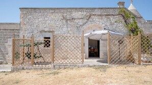 Un edificio de piedra con un portón de madera, un arco de entrada y una pequeña zona techada.