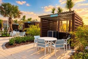 Un espace extérieur aménagé en terrasse, avec un coin salon couvert, une table et des chaises, ainsi qu’un panneau indiquant « Cobana 3 ».