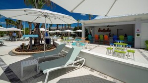 A poolside area with lounge chairs, umbrellas, and a bar area with colorful chairs. - Super Modern 7BR Windsor Cay* (Clermont)