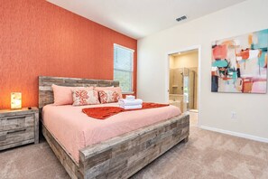 Une chambre à coucher avec un lit en bois, une table de chevet, une lampe de chevet et un grand tableau abstrait accroché au mur.