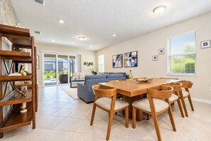 A spacious living area with a dining table, sofas, and a bookshelf.