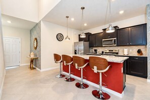 A modern kitchen with dark cabinets, a red island, and bar stools.
