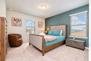 Une chambre à coucher avec un lit, une chaise, une commode et des œuvres d’art accrochées aux murs.