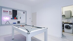 A clean, modern room with a pool table, a neon sign, and a washing machine visible through an open door. - Sleep 7, Pool Table/TTennis, Free Parking, 3BR (Manchester)