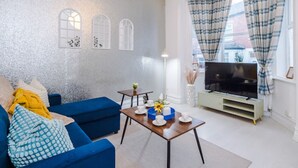 A modern living room with a blue sofa, a wooden coffee table, and a flat-screen TV. - Sleep 7, Pool Table/TTennis, Free Parking, 3BR (Manchester)