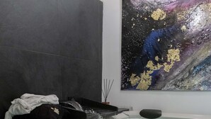 Una habitación con una bañera grande, un cuadro en la pared y una mesa con copas y botellas de vino.