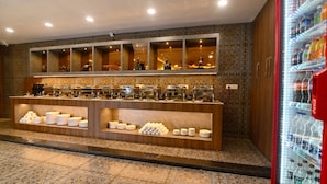 A buffet area with multiple serving stations, a beverage refrigerator, and patterned floor tiles. - Carry Plus Hotel (Indore)
