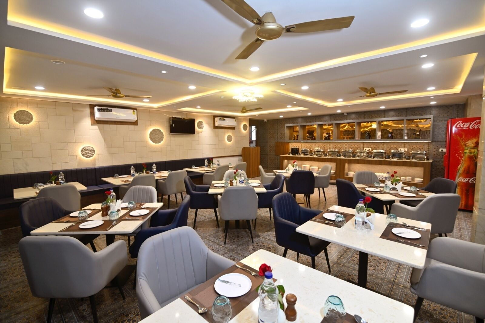 A restaurant with multiple tables and chairs, ceiling fans, and a bar area.