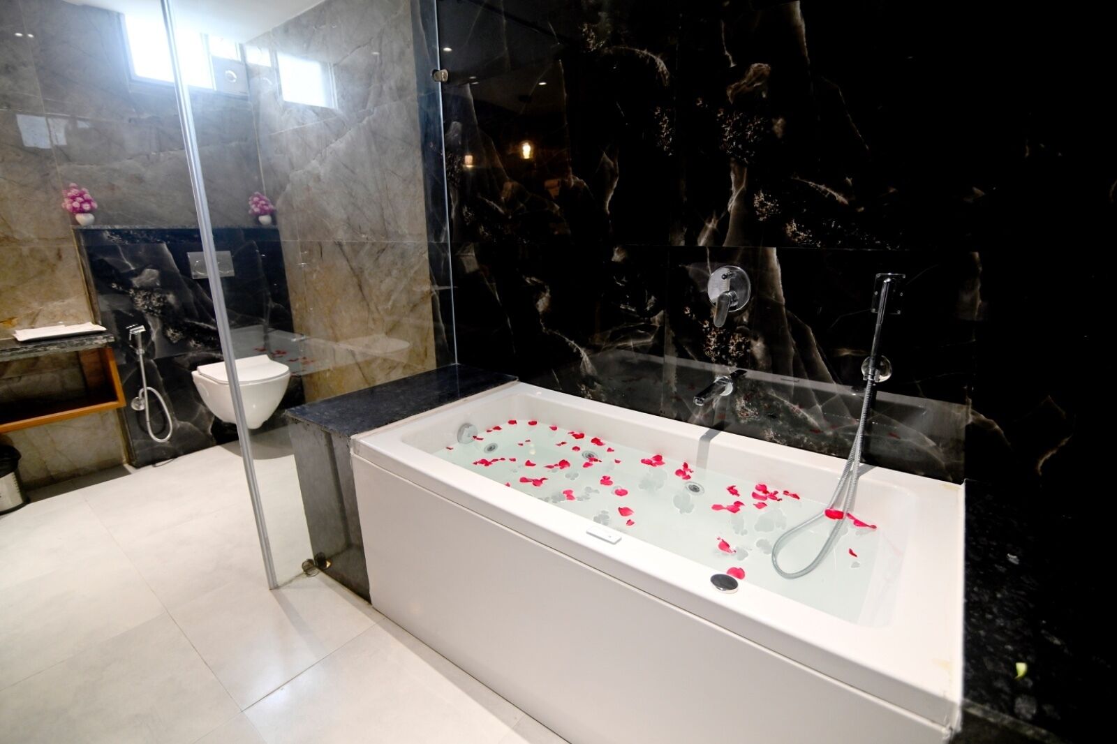Ein modernes Badezimmer mit einer in Glas eingefassten Badewanne, Toilette und Duschbereich.