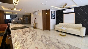 A modern hotel lobby with marble flooring, a sofa, a desk, and a ceiling fan. - Carry Plus Hotel (Indore)