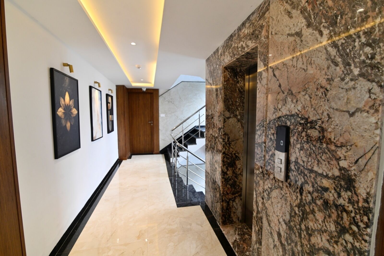 A modern hallway with marble flooring, a wooden door, and a wall-mounted elevator.