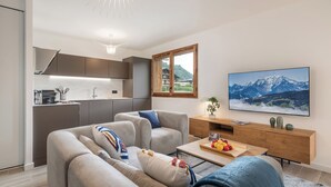 A modern living room with a sofa, coffee table, and a TV mounted on the wall.