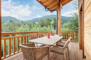A wooden deck with a table and chairs, overlooking a forested valley.