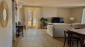 Een woonkamer met een bank, televisie en eethoek.