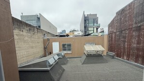 Una terrazza sul tetto con superficie piana, un piccolo angolo relax e vista sugli edifici circostanti.