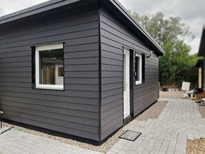 A modern house with dark siding, a front door, and two windows. - Outside Ribe Guesthouse (Ribe)