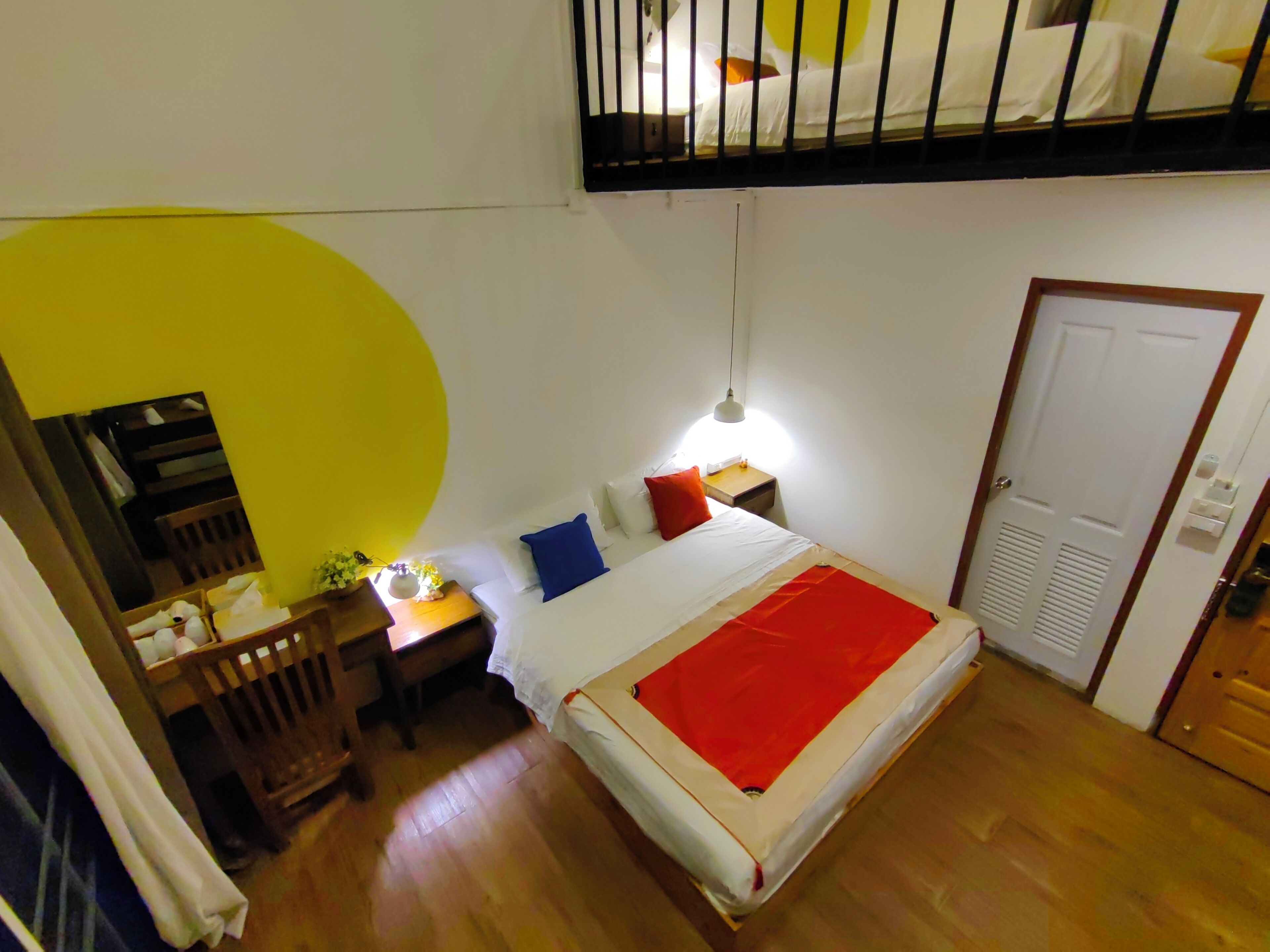Ein Schlafzimmer mit einem Etagenbett, einem Nachttisch mit Lampe, einem Schreibtisch mit Stuhl und einem Kleiderschrank.