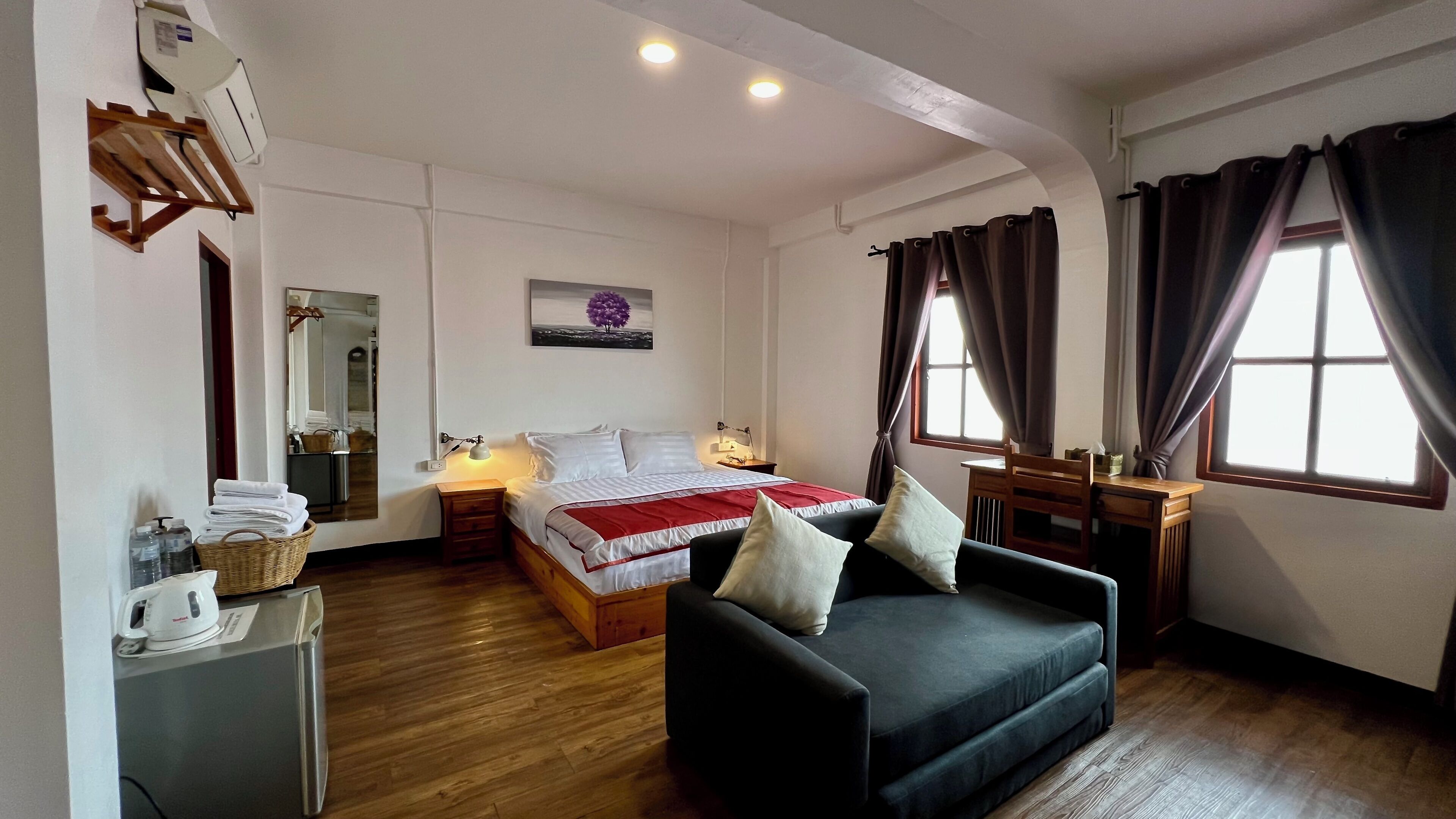 Una habitación de hotel con cama, sofá, escritorio y ventana con cortinas.