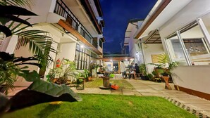 A courtyard with potted plants, a fire extinguisher, and a paved walkway.