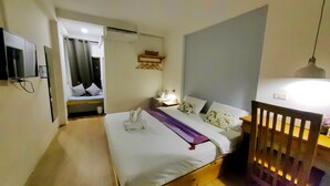 A modern bedroom with a wooden bed, a bedside table with a lamp, and a TV mounted on the wall.