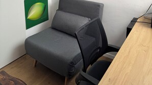 A modern room with a gray sofa, a wooden desk, and a cityscape painting. - Office/apartment combo Rothschild Blv in TelAviv! Parking, elevator, shelter (Tel Aviv-Yafo)