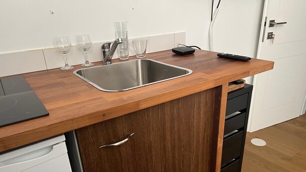 A kitchen with a wooden countertop, stainless steel sink, and a black remote control on the counter. - Office/apartment combo Rothschild Blv in TelAviv! Parking, elevator, shelter (Tel Aviv-Yafo)