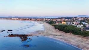 A coastal town with a beach, houses, and mountains in the background. - Praia Grande Hotel (Fundão)