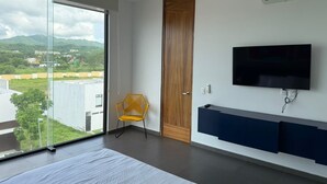 A modern bedroom with a large bed, a TV mounted on the wall, and a sliding glass door leading to a balcony. - Escapada junto al mar en B Nayar (Cruz de Huanacaxtle)