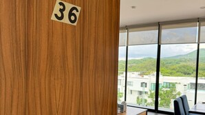 A hotel room with a wooden door labeled '36', a large window offering a view of a cityscape and greenery, a modern dining area with a table and chairs, and a minimalist interior design. - Escapada junto al mar en B Nayar (Cruz de Huanacaxtle)