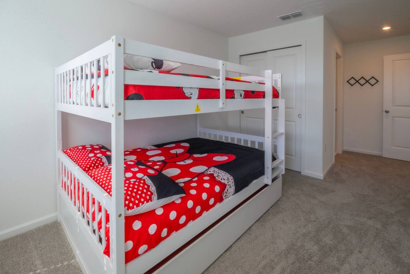 Ein Stockbett mit rot-weißer Punkteoptik, weißen Geländern und einem Teppichboden.