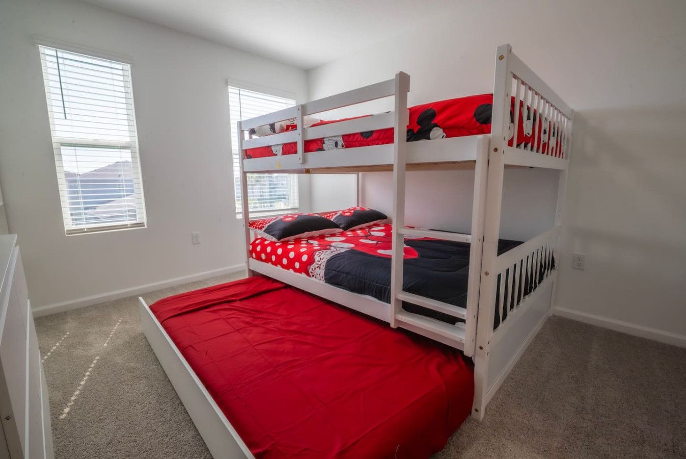 Una cama litera con ropa de cama roja y una almohada con temática de Mickey Mouse.