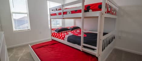 Un lit superposé avec une literie rouge et un coussin à l’effigie de Mickey Mouse.