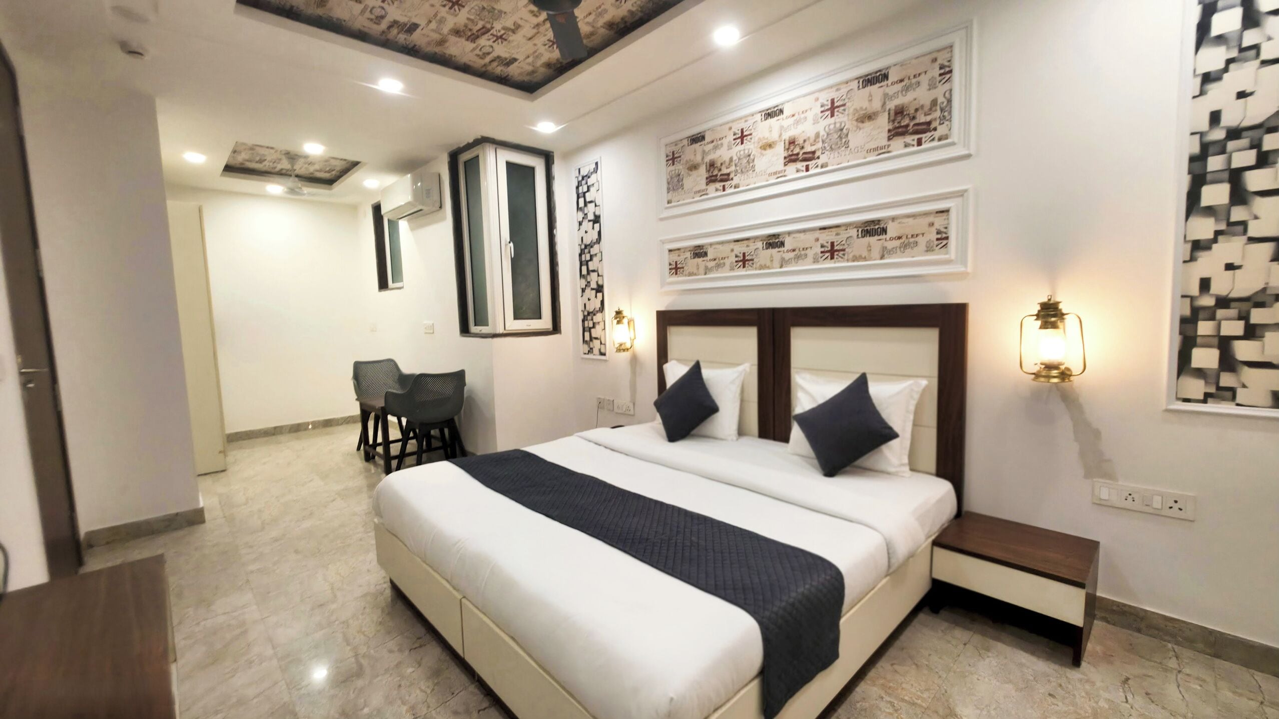 Une chambre d’hôtel avec un grand lit, un bureau, deux chaises et des œuvres d’art accrochées aux murs.